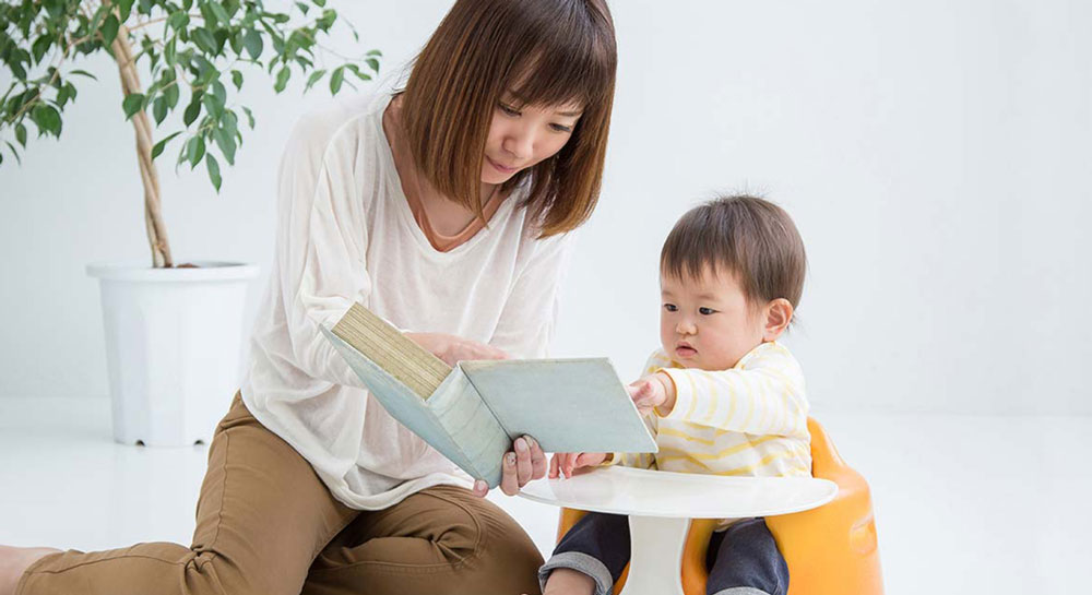 赤ちゃんに絵本を読んであげる女性